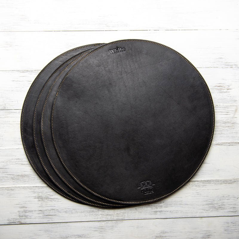 Circle personalized fine leather placemat in dark brown with stitching detail.